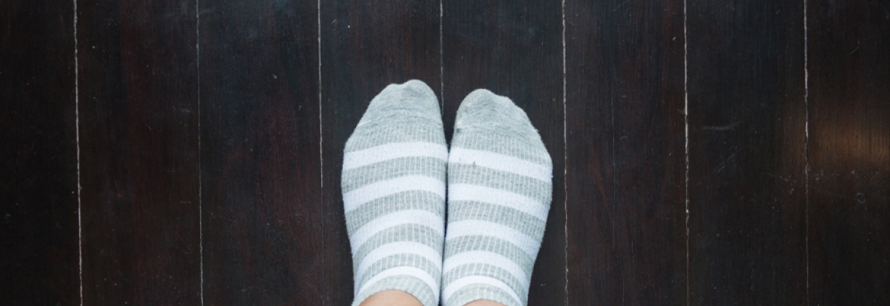 pair of feet with socks on hardwood floors